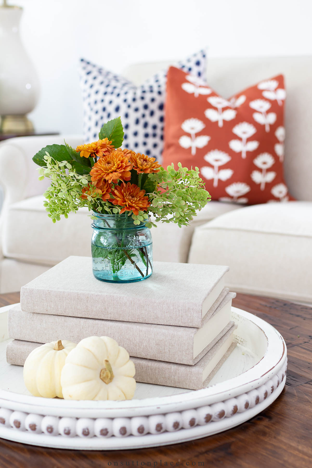 https://www.onsuttonplace.com/wp-content/uploads/2023/09/fall-decorating-coffee-table-idea-tray-books-flowers-pumpkins.jpg